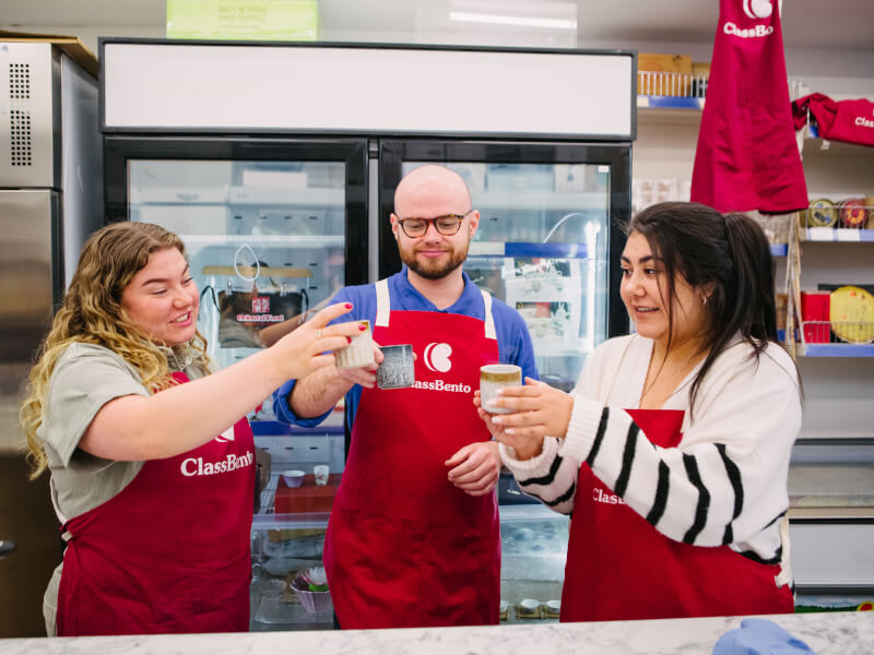 Three people wearing pink aprons tasting tea